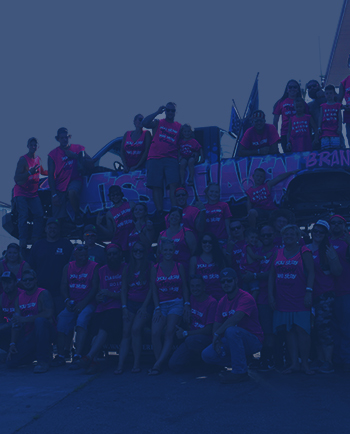 An automotive club standing atop and around a monster truck.